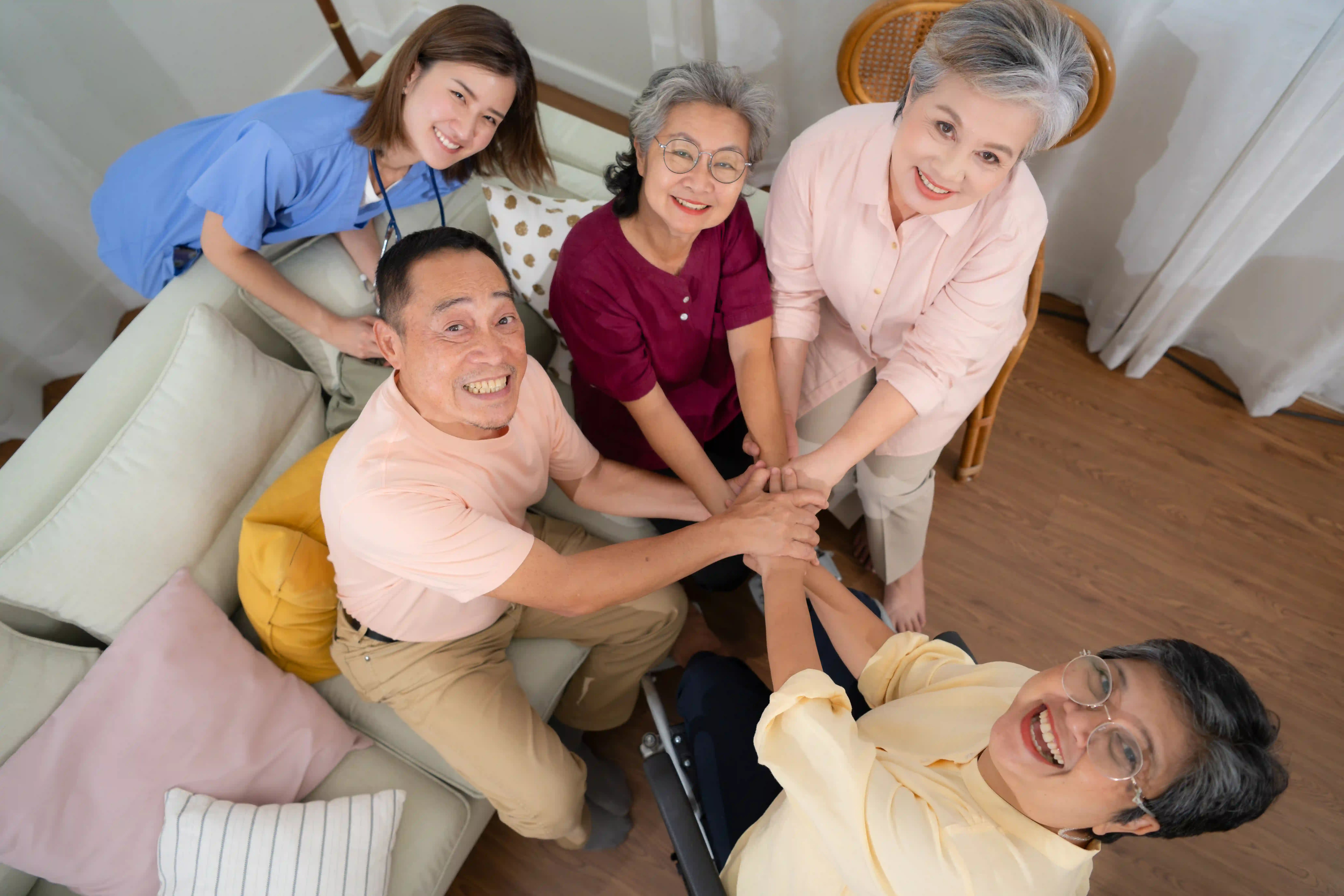 Group home residents and caregiver joining hands together